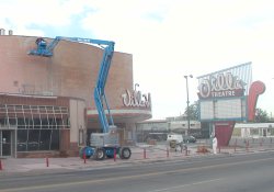 Workmen on a crane remove the pink paint from the the Villa Theatre's brick exterior